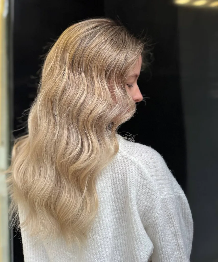 Păr vopsit blond bej, lung și ondulat în valuri largi, văzut din profil