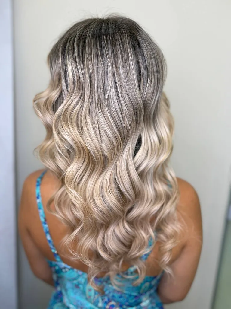 Păr lung cu rădăcină închisă și balayage blond bej, cu bucle