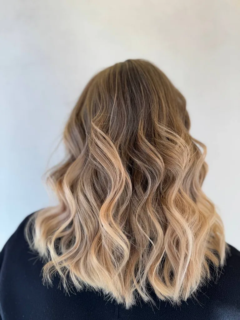 Ombré de la șaten la blond piersică pe păr ondulat, lungime medie