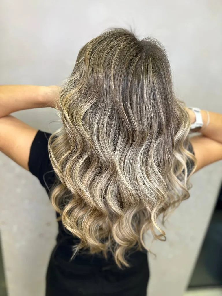 Balayage blond pe păr lung cu rădăcină șatenă și bucle