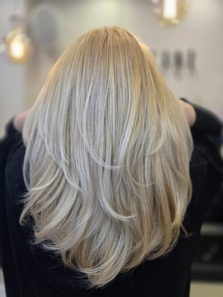 Păr lung blond cald, tuns în straturi, văzut din spate
