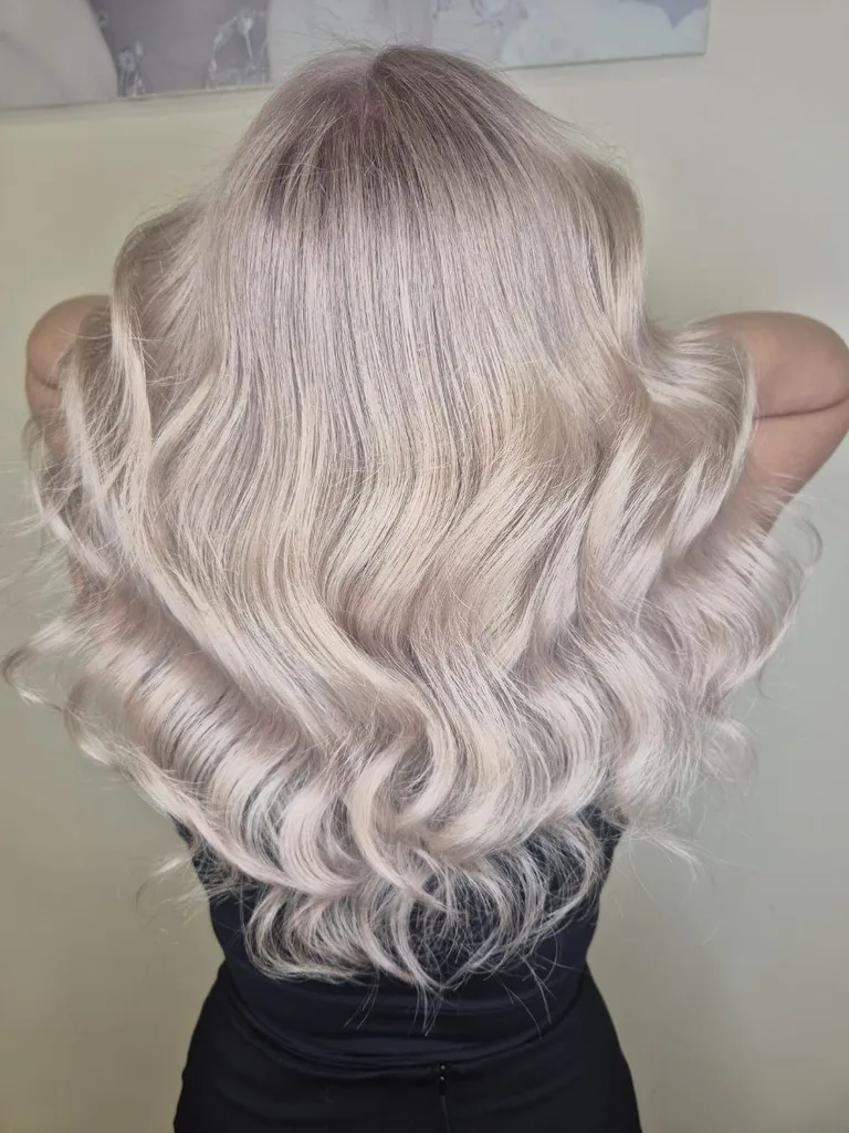 Păr lung blond perlat cu nuanță rozalie și rădăcină umbrită, ondulat