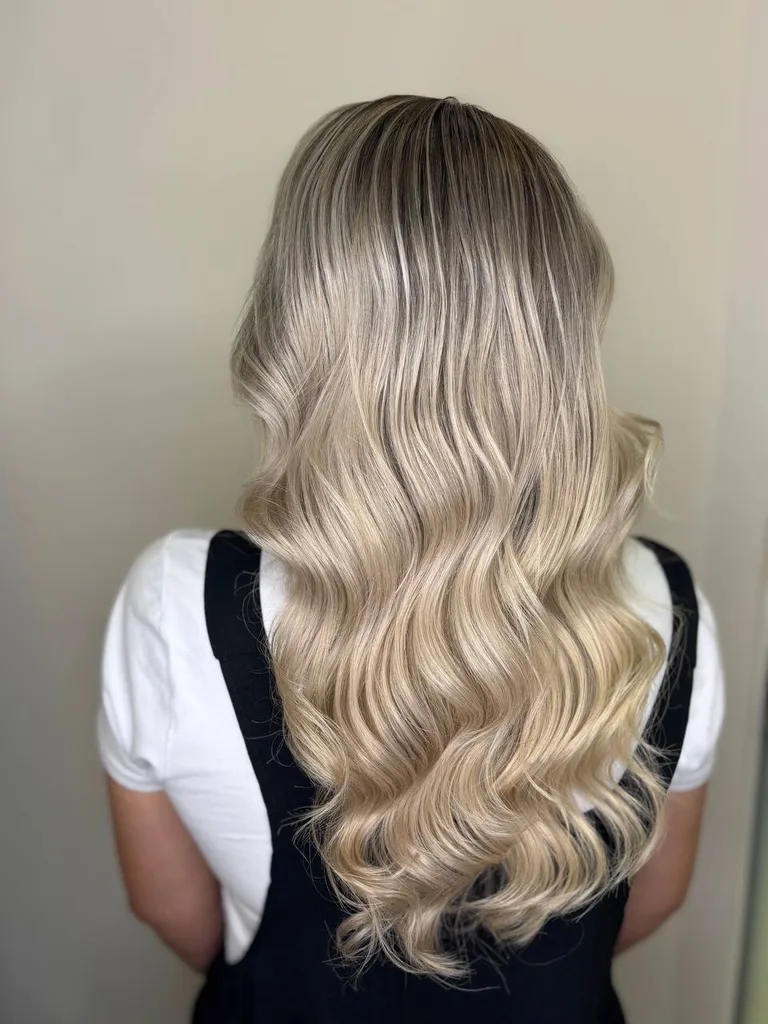 Păr lung blond cu rădăcină umbrită și bucle, văzut din spate